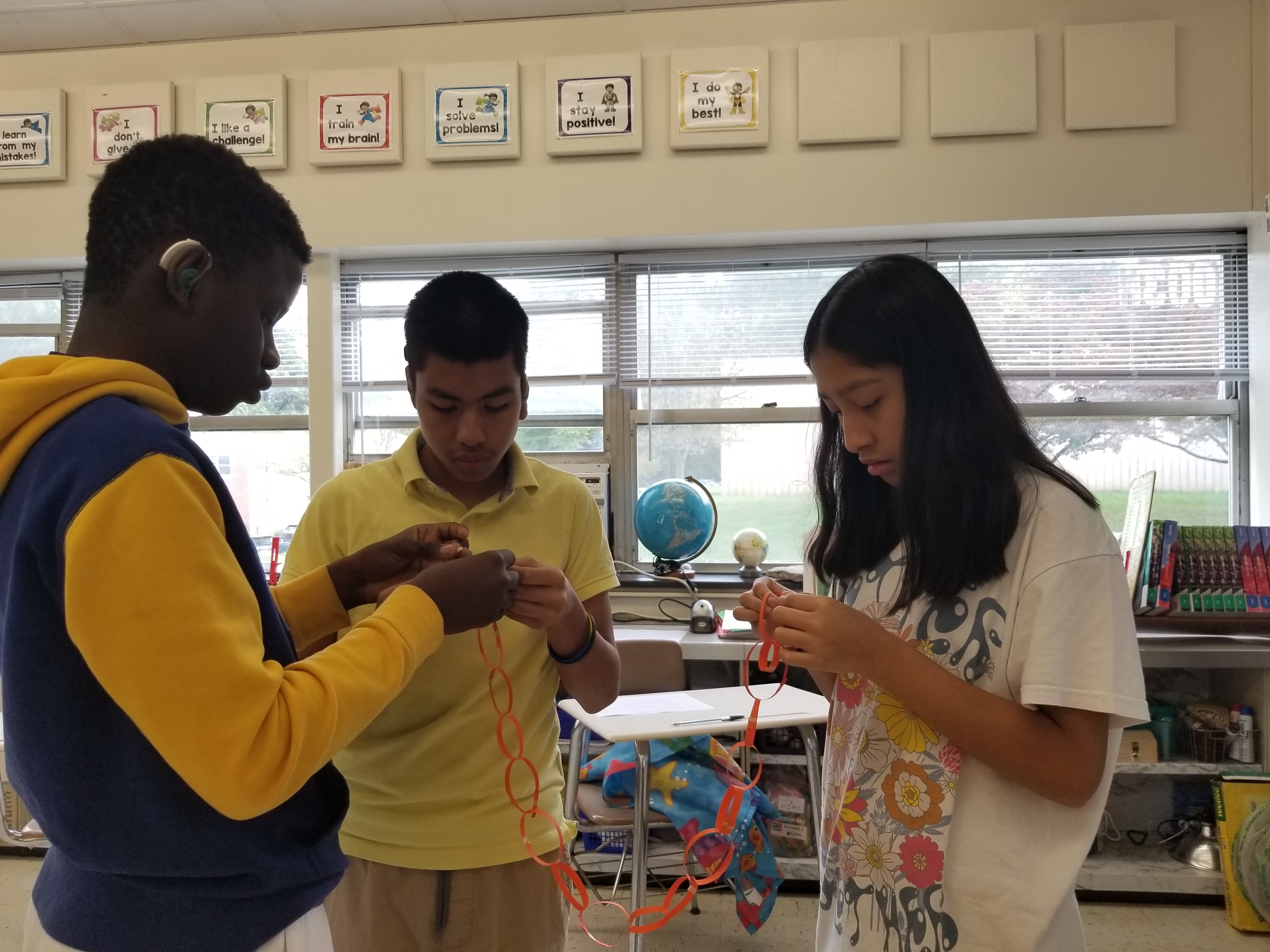 middle school students 2 boys 1 girl adding rings to a paper chain